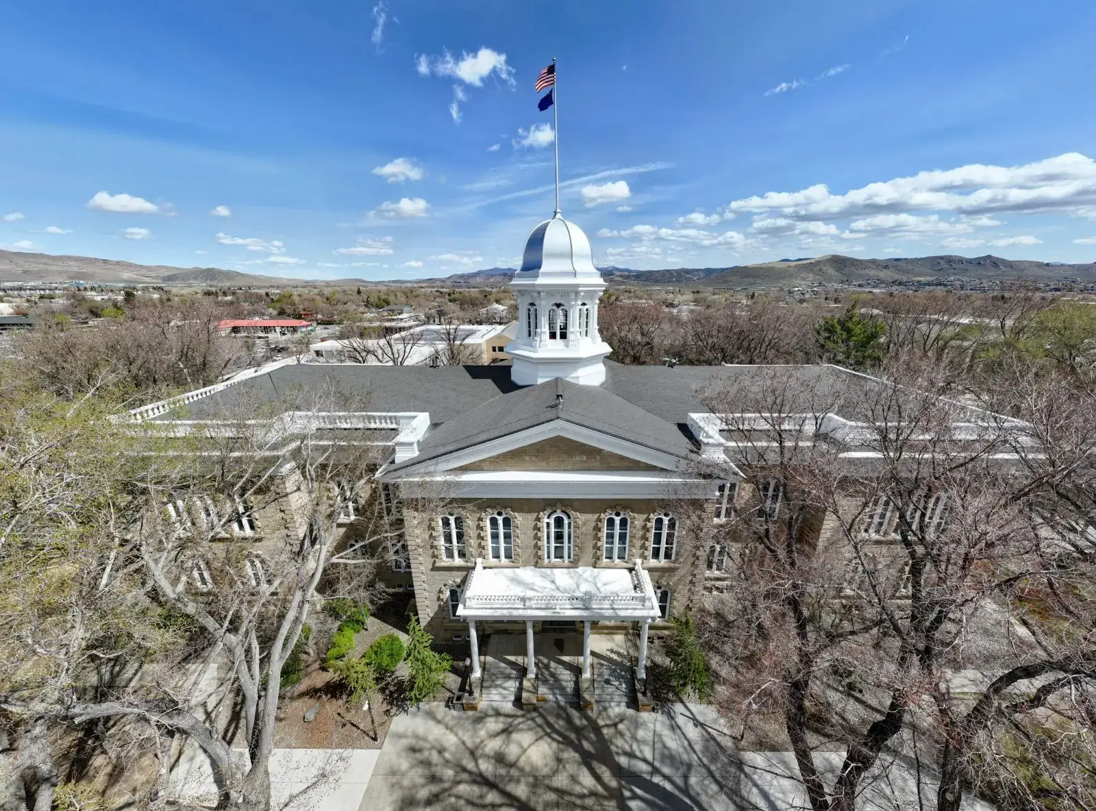 Historic white-domed courthouse under a blue sky with an American flag.